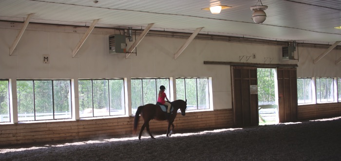 Chrislar Indoor Arena with student riding a horse